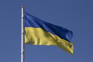 fechar acima do acenou ucraniano bandeira em mastro de bandeira foto