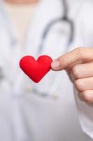 médico mão segurando vermelho coração forma dentro hospital. amor, doador, mundo coração dia, mundo saúde dia, csr doação e seguro conceitos foto