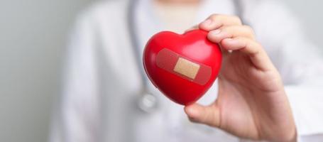 médico mão segurando vermelho coração forma dentro hospital. amor, doador, mundo coração dia, mundo saúde dia, csr doação e seguro conceitos foto