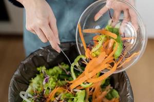 composto a cozinha desperdício, reciclando, orgânico refeição ásia jovem família mulher raspagem, jogando Comida sobras para dentro a lixo, Lixo bin a partir de vegetal. ambientalmente responsável, ecologia. foto