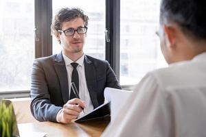 ásia jovem gerente, Empregador homem entrevista com pessoa, ter questão sobre currículo e ouço para candidato responder, conversação juntos às escritório. recrutamento empregado trabalho conceito. foto