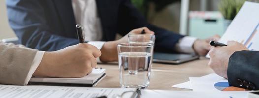 o negócio reunião, ásia grupo homem, mulher chuva de ideias analisando gráfico dados do custo plano, discutindo dentro borda sala, usando touchpad ou computador portátil computador em mesa ou escrivaninha. pessoas trabalhando conferência sala. foto