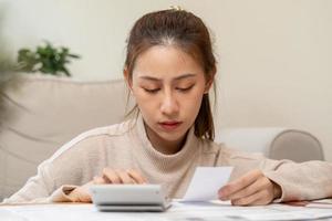 financeiro devo ásia jovem mulher, menina sentado sofrer, estressado e confuso de calcular despesa a partir de fatura ou conta, ter não dinheiro para pagar, hipoteca ou empréstimo. dívida, falência ou falência conceito. foto