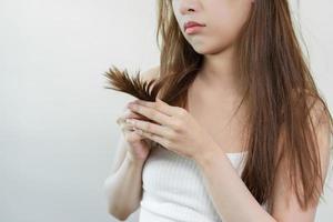 estragado cabelo, frustrado ásia jovem mulher, menina mão dentro segurando divisão termina, bagunçado não escovado seco cabelo com face choque, grandes desgrenhado cabelo, saúde Cuidado do beleza. retrato isolado em fundo. foto