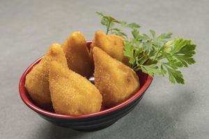 tradicional frito coxinha dentro prato em ardósia fundo, popular brasileiro lanche foto