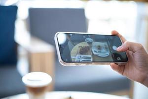 mulher levando uma cenário do Comida com uma Móvel telefone dentro uma cafeteria foto