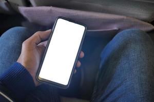 mão segurando o telefone inteligente com tela vazia em um carro foto