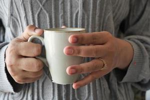 feche a mão de uma mulher segurando uma caneca de café foto