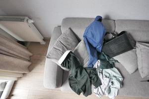 bagunçado roupas em sofá às casa foto