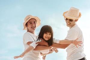 feliz ásia família apreciar a mar de praia às consistindo pai, mãe e filha tendo Diversão jogando de praia dentro verão período de férias em a oceano de praia. feliz família com Férias Tempo estilo de vida conceito. foto