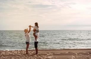 feliz ásia família apreciar a mar de praia às consistindo pai, mãe e filha tendo Diversão jogando de praia dentro verão período de férias em a oceano de praia. feliz família com Férias Tempo estilo de vida conceito. foto