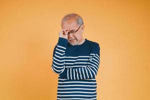 ásia Senior homem sentindo-me dor de cabeça ou enxaqueca dor em a amarelo fundo. foto