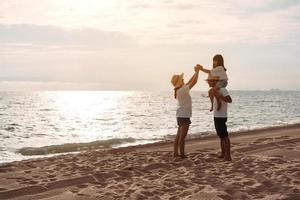 feliz ásia família apreciar a mar de praia às consistindo pai, mãe e filha tendo Diversão jogando de praia dentro verão período de férias em a oceano de praia. feliz família com Férias Tempo estilo de vida conceito. foto