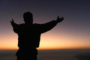 silhueta do uma homem Rezar em a montanha às nascer do sol, lindo paisagem, espiritualidade e religião, homem Rezar para Deus. cristandade conceito. foto