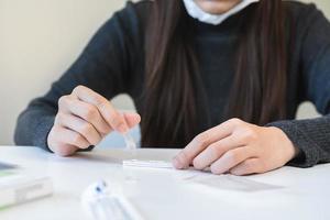 pandemia do doença, ásia jovem mulher, menina mão segurando atk, antígeno kit auto teste. apresentando dispositivo nasal, nariz cotonete teste para possível infecção do coronavírus, covid-19 às lar. saúde Cuidado. foto