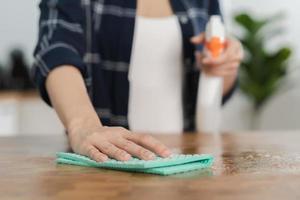 mão do ásia jovem mulher mão limpeza de madeira mesa, gabinete, usando trapo esfregar pó, segurando spray garrafa dentro cozinha às lar. família higiene limpar \ limpo acima, limpador pessoas, equipamento ou ferramenta para limpeza. foto