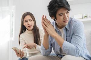 infidelidade, suspeita ásia jovem casal amor luta relação, esposa segurando celular, Smartphone traindo em telefone, repreensão marido sobre desconfiança, desconfiança e ciúmes quando sentado às lar. foto