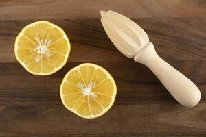 Limão fatiado com um alargador de madeira em uma mesa de madeira