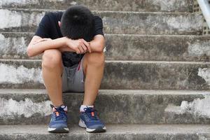 depressivo Garoto senta sozinho ar livre, triste e chorar, face baixa entre dele joelhos. conceito, emoção, sentimento. desapontado infeliz culpado . Garoto é intimidado e punido. sozinho. foto