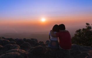 irmão e irmã sentado em Rocha e Vejo pôr do sol juntos foto