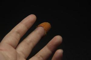 desgastado Fora molhado dedo Castanho ferida gesso foto em meio dedo isolado em Sombrio Preto fundo.
