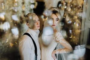 a encantador casal se beijando dentro a do hotel lobby perto a lustre foto