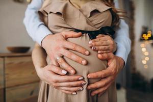 as mãos do homem abraçam a barriga da mulher grávida foto