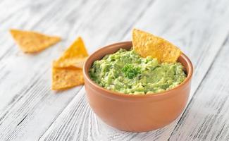 tigela de guacamole com chips de tortilha foto