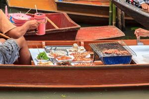 a barco este vende frutos do mar em maldição Saduak flutuando mercado é uma popular turista destino este europeus e chinês pessoas amor para viagem com tradicional maneiras do aldeões. foto