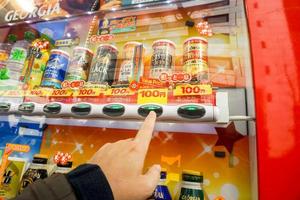 otaru, Japão, 2018 mão do 1 pessoas pressionando para Comprar enlatado suave beber a partir de desconto beber vending máquina. foto