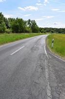 país estrada com mau rachaduras e verde Relva foto