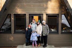 família com três crianças contra de madeira cabine minúsculo casa. crianças dentro interior. foto