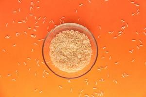 close-up de arroz integral de grãos longos em fundo laranja foto