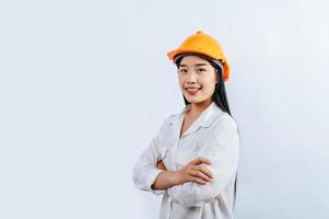 jovem fêmea engenheiro vestindo amarelo capacete ficar de pé com encantador sorrir postura foto