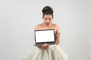 pose de noiva linda jovem asiática com computador portátil de maquete na mão foto