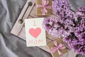 uma ramalhete do lilases e uma cartão com a texto Eu amor mãe em uma bandeja. mãe dia conceito foto