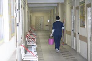 uma limpeza senhora é caminhando ao longo a corredor do uma hospital ou clínica. foto