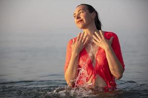 lindo idosos mulher banha dentro a mar e salpicos água. foto