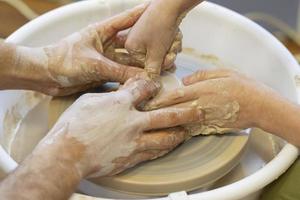 a oleiro ensina a criança a arte. fechar-se do uma de oleiro mãos e uma criança mão com a item em uma de oleiro roda. trabalhando com argila. argila mestre aula. foto