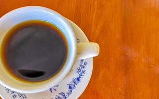 pote de xícara branca azul com mesa de madeira de café preto méxico. foto