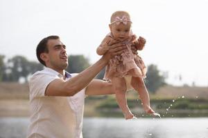 feliz Papai lança acima com dele pequeno filha para uma andar. paternidade. foto