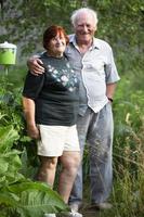 uma lindo muito idosos casal abraços e parece às a Câmera às a dacha. foto