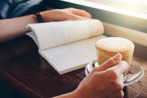 cortada tiro do mulheres mãos levar uma café pausa com lendo uma livro. foto