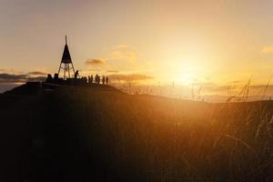 a lindo pôr do sol e a silhueta do turista em a cume do mt.eden a icônico vulcão dentro auckland, Novo zelândia. foto