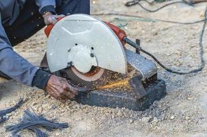 do homem mão usando ferro cortador dentro a ambiente de trabalho, fixação ferro marquise quadro, Armação com fagulha. trabalhador corte aço com elétrico ferro cortador. aço cortador moedor corte ferro tubo com brilhante faíscas. foto