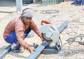 Sakon nakhon, Tailândia - fevereiro 10, 2022, homem trabalhador usando ferro cortador dentro a ambiente de trabalho, fixação ferro marquise quadro, Armação com fagulha. trabalhador corte aço com a elétrico ferro cortador. foto