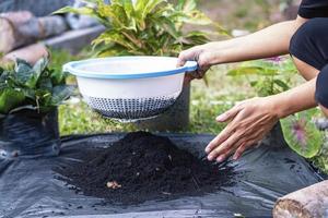 preparação de mistura de solo de composto fértil, húmus e vermiculita no chão de saco de lixo preto no jardim. misturar os componentes do solo para a preparação do substrato para o transplante de plantas. foto