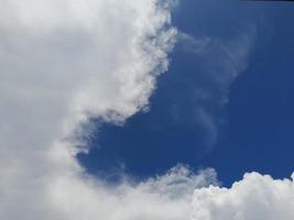 lindas nuvens brancas sobre fundo de céu azul profundo. grandes nuvens fofas e brilhantes cobrem todo o céu azul. foto