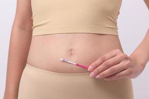 fechar acima mulher usando ovalação lh teste ou hcg gravidez teste em branco fundo foto