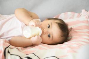 uma bebê menina é bebendo leite garrafa, família, criança, infância e paternidade conceito foto